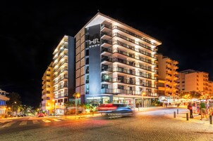 A multi-story hotel with balconies, a prominent 'HR' sign, and a well-lit entrance.