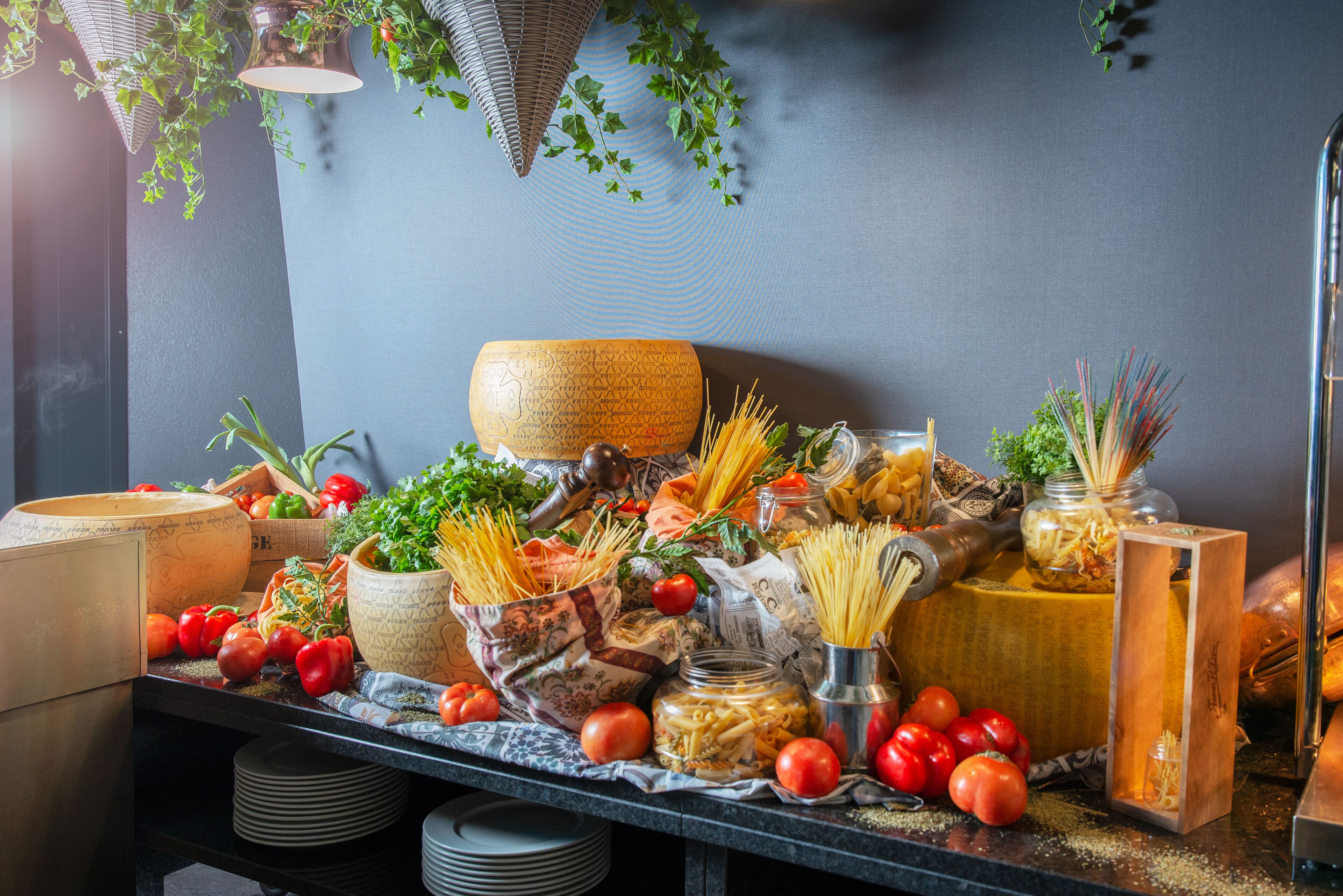 Une table sur laquelle se trouvent divers aliments et ustensiles de cuisine, notamment des tomates, des pâtes et un saladier en bois.
