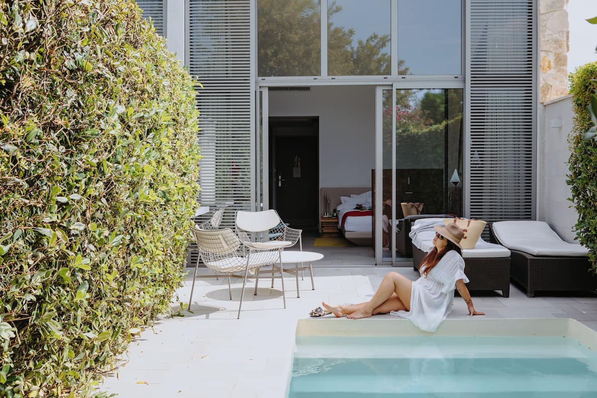 Ein moderner Poolbereich im Freien mit Liegestühlen und einer Glastür zum Schlafzimmer.
