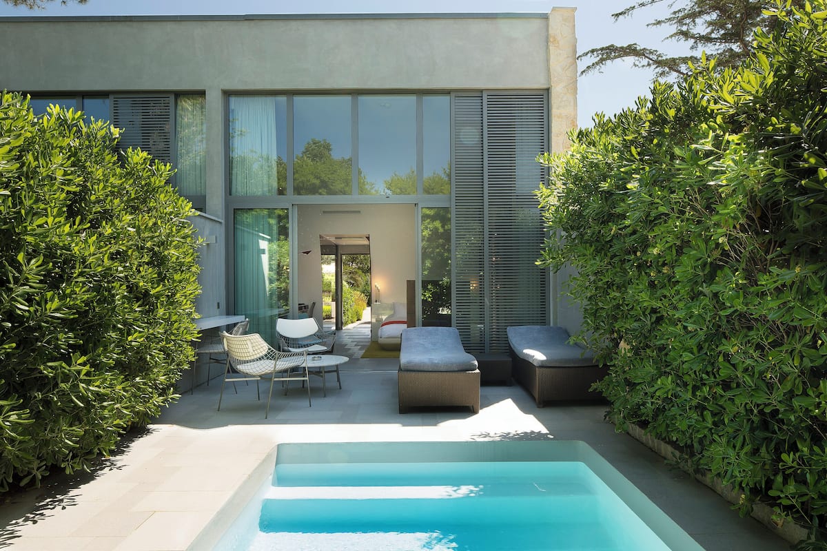 Ein moderner Poolbereich im Freien mit Sitzgelegenheiten und Blick auf das Haus.