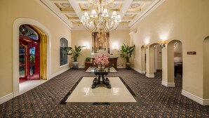 A grand hallway with a central table, potted plants, and a chandelier.