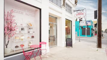 A storefront with a sign reading "Sweet Corner Coffee Pastry Cakes" and a display of desserts.