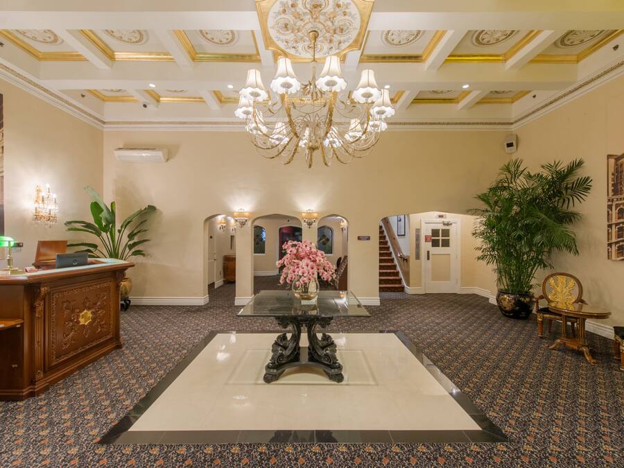 Um hall de entrada com um lustre imponente, uma recepção e uma escadaria que leva aos andares superiores.