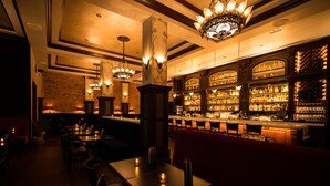 A bar area with multiple seating options, a well-stocked liquor display, and decorative lighting fixtures.