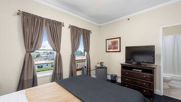 A hotel room with a bed, a television, a dresser, and a window with curtains.