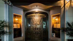 A grand entrance with a decorative metal door labeled "EDMCN" and two illuminated windows on either side.