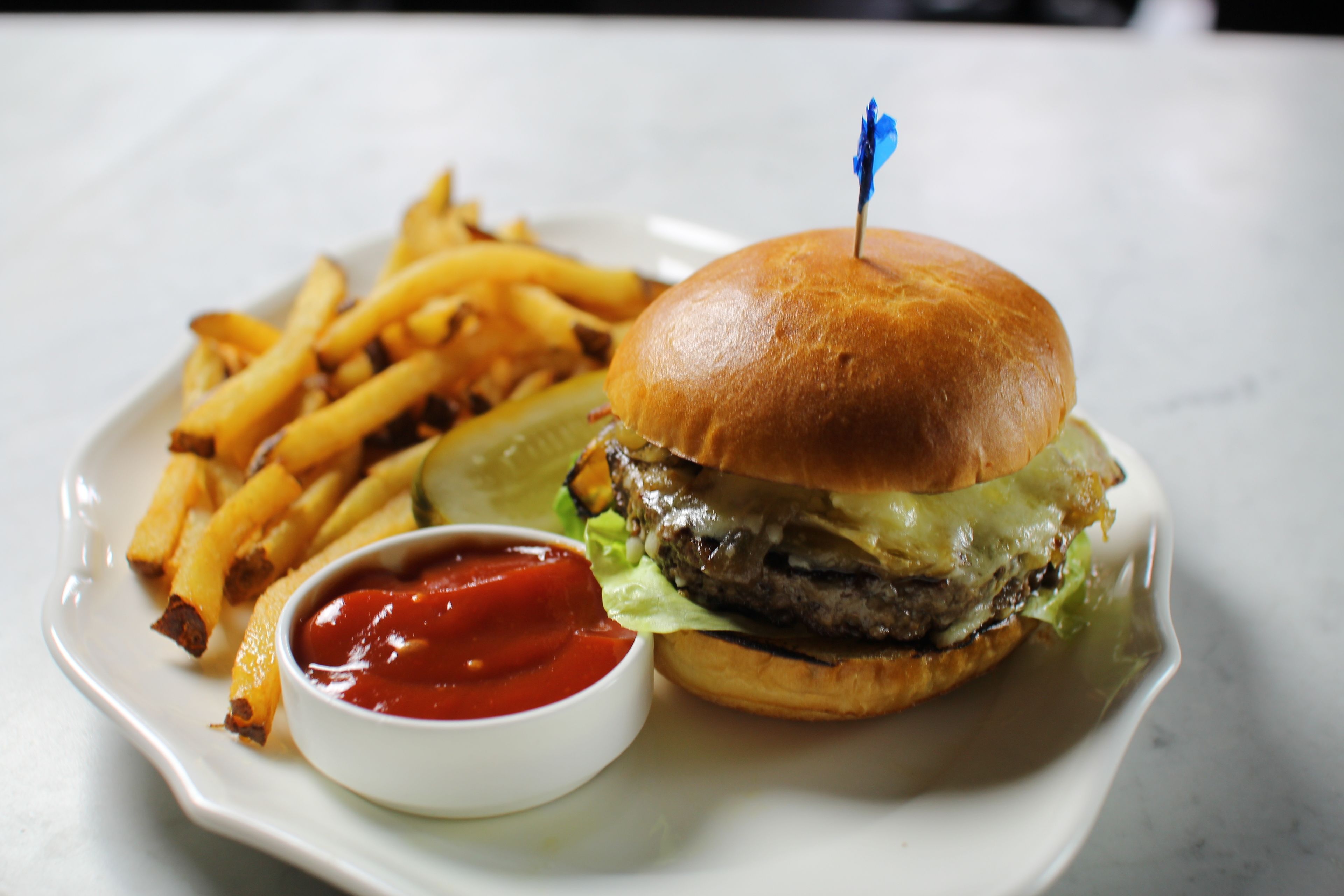 A plate with a burger, fries, and ketchup.
