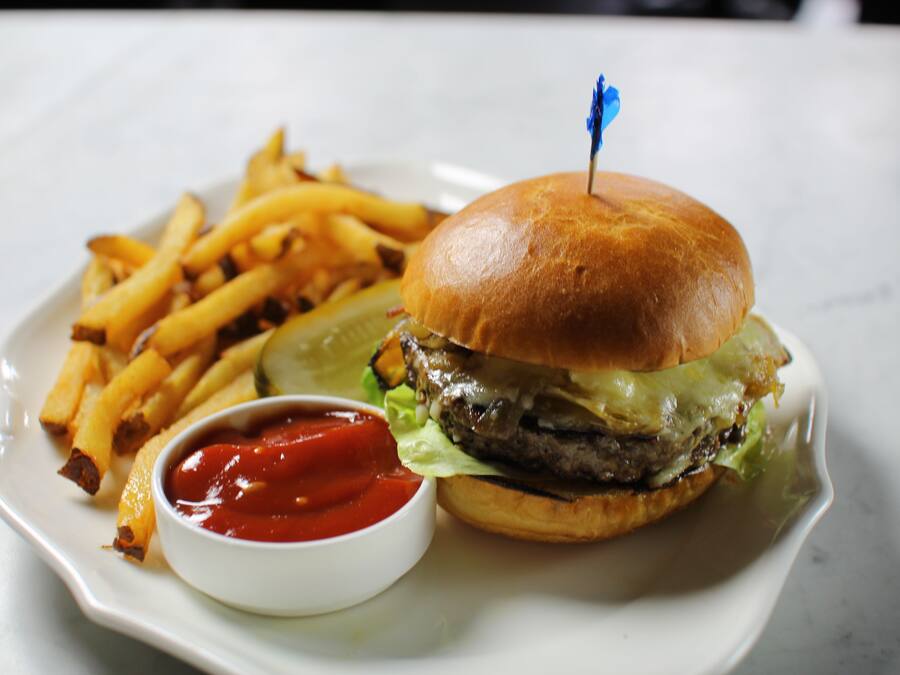 Un plat amb una hamburguesa, patates fregides i ketchup.