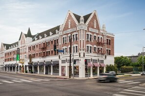 A historic building with a corner location, featuring a prominent entrance, multiple windows, and a fire escape.