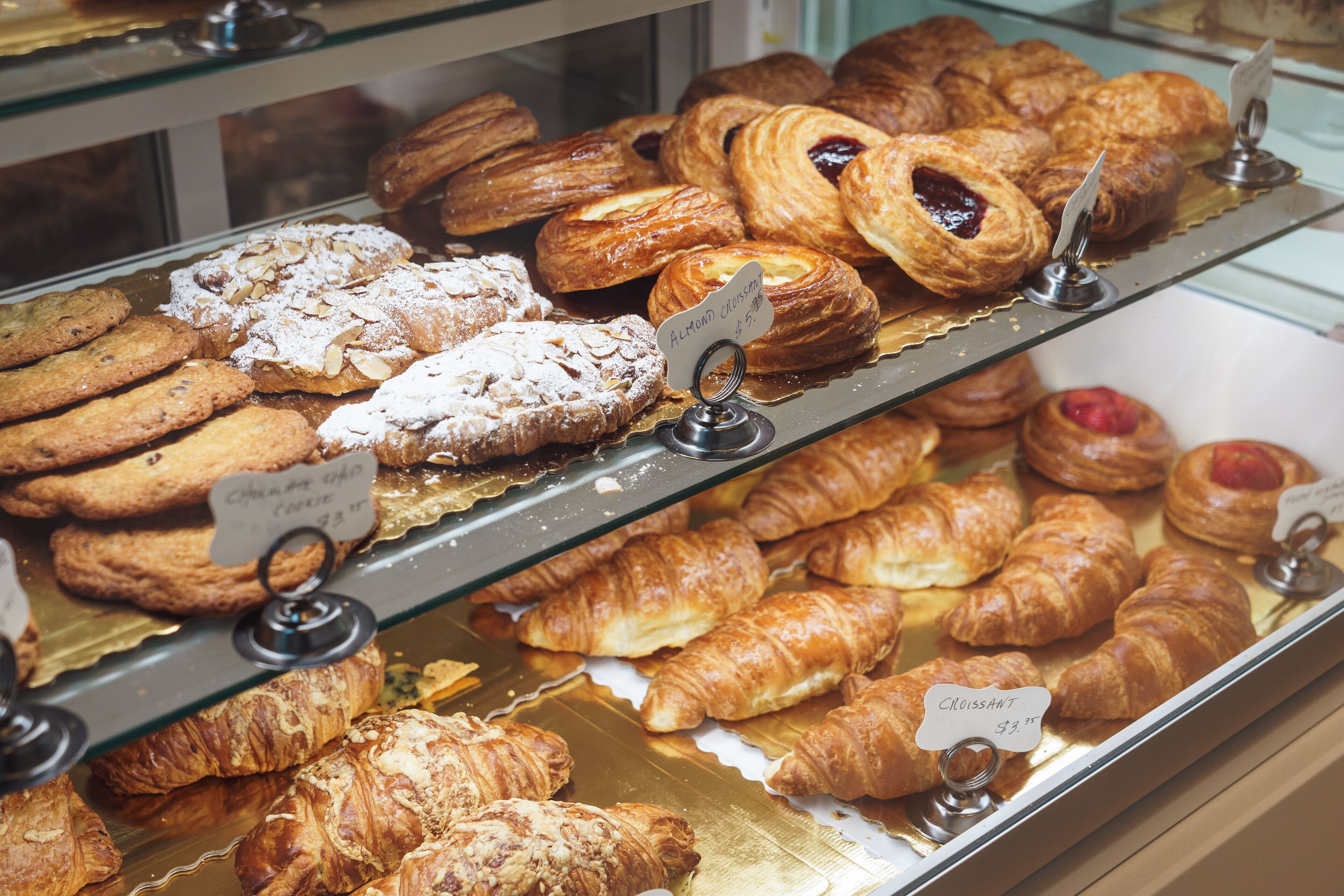 Una vetrina di pasticceria con diversi dolci e biscotti, tra cui croissant e amaretti.