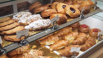 Una vetrina di pasticceria con diversi dolci e biscotti, tra cui croissant e amaretti.