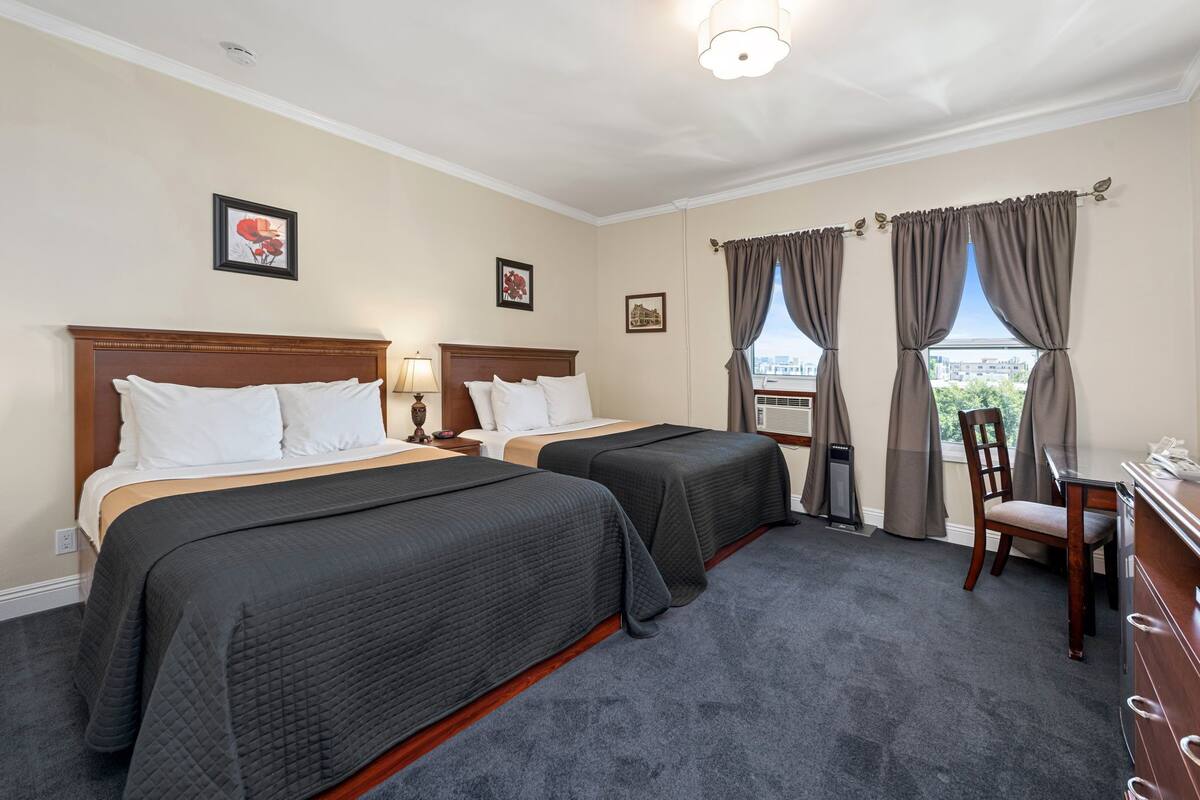 A hotel room with two beds, a desk, and a chair.