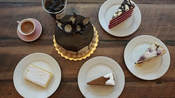 A dessert table with various cakes and a cup of coffee on a wooden table.