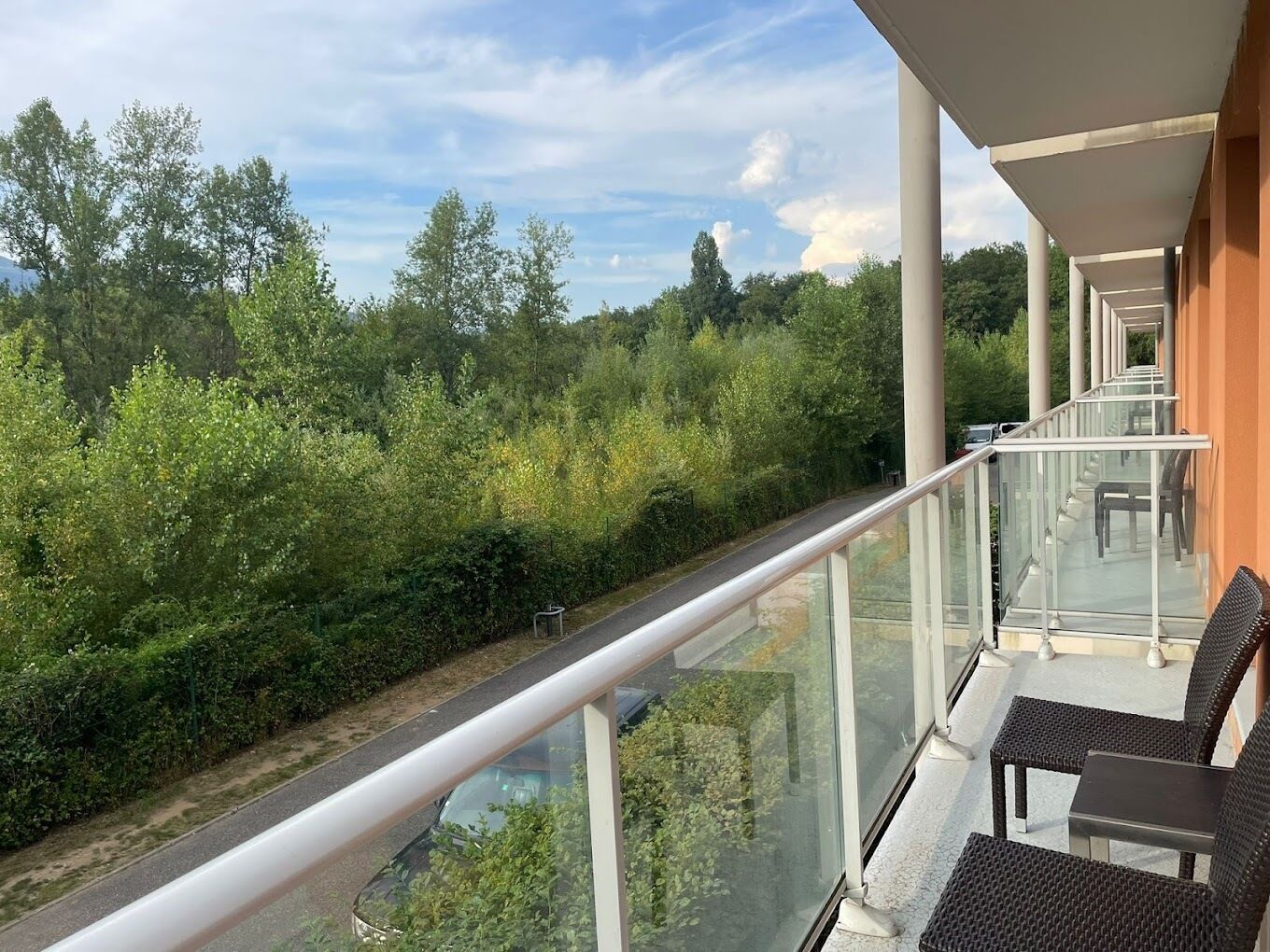 A balcony with glass railings overlooking a lush green landscape.