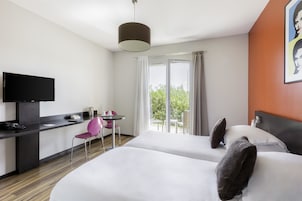 Quarto de hotel com duas camas, uma mesa de trabalho, televisão de tela plana, uma cadeira e uma mesa.
