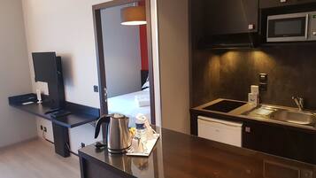 A modern kitchen with a microwave, stove, and sink. There is a coffee maker and a kettle on the counter.