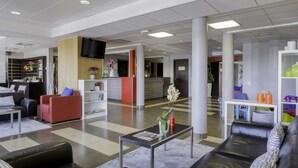 A modern lobby with a reception desk, seating areas, and a TV mounted on the wall. - Best Western Park Hotel Geneve-Thoiry (Thoiry)