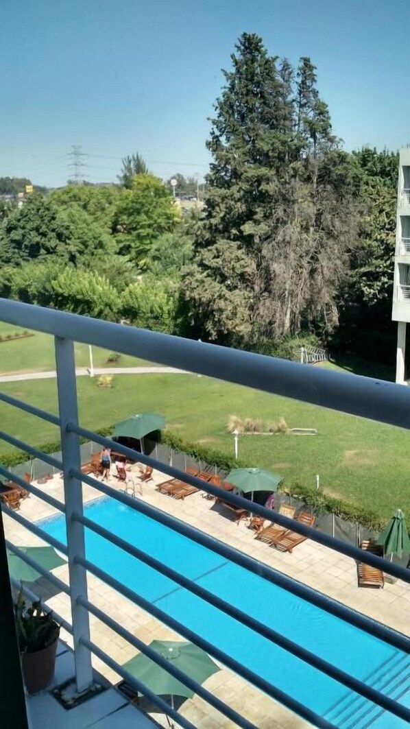 A pool area with lounge chairs and umbrellas, surrounded by greenery and trees. - Concord Pilar Apart Suite 313 - Almendros (La Lonja)