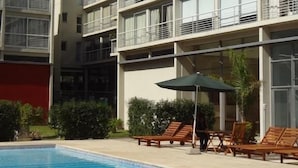 A modern hotel with a swimming pool, multiple balconies, and outdoor seating.