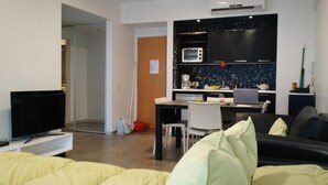 A modern living room with a sofa, a TV, and a dining area with a table and chairs.