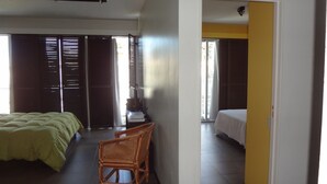 A hotel room with a bed, a chair, a desk with a computer, and a window with blinds.