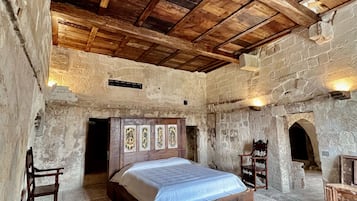Ein rustikales Schlafzimmer mit einem hölzernen Bett, Steinwänden und einem Fischgrätparkett.