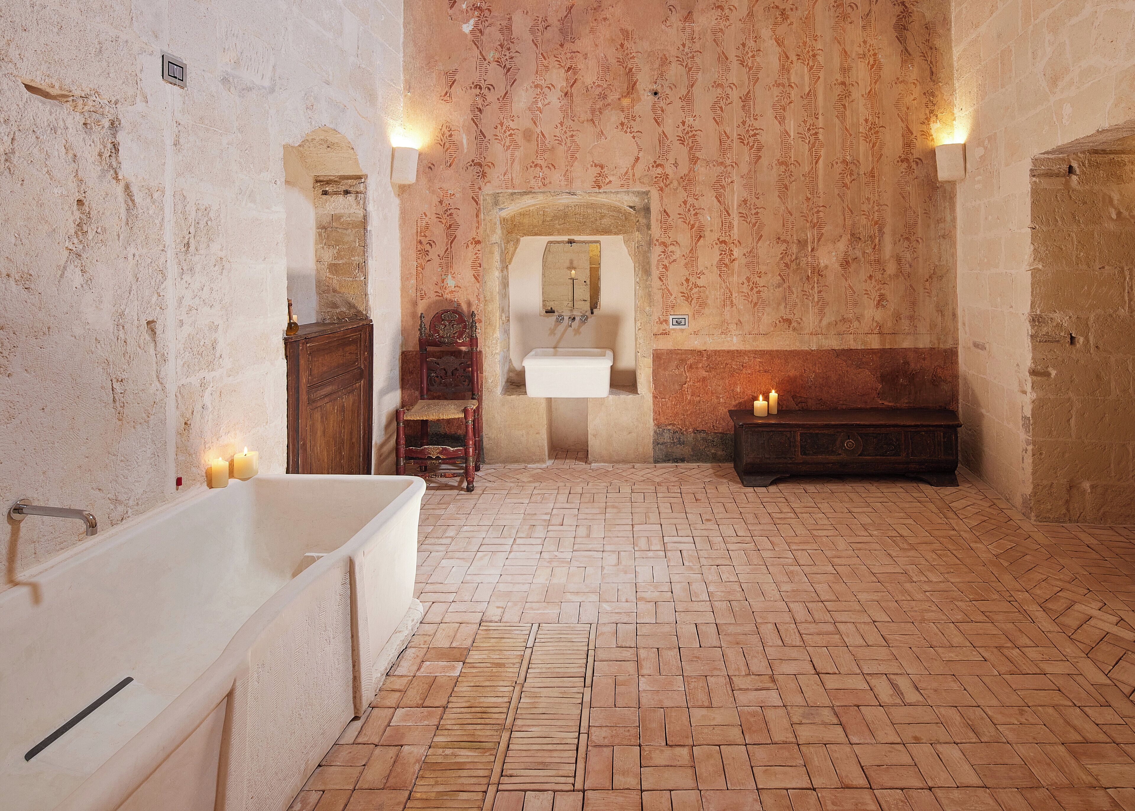 Un baño histórico con una bañera grande, un banco de madera y una silla.