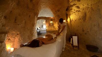 A spa room with a massage table, candles, and a wooden chair.