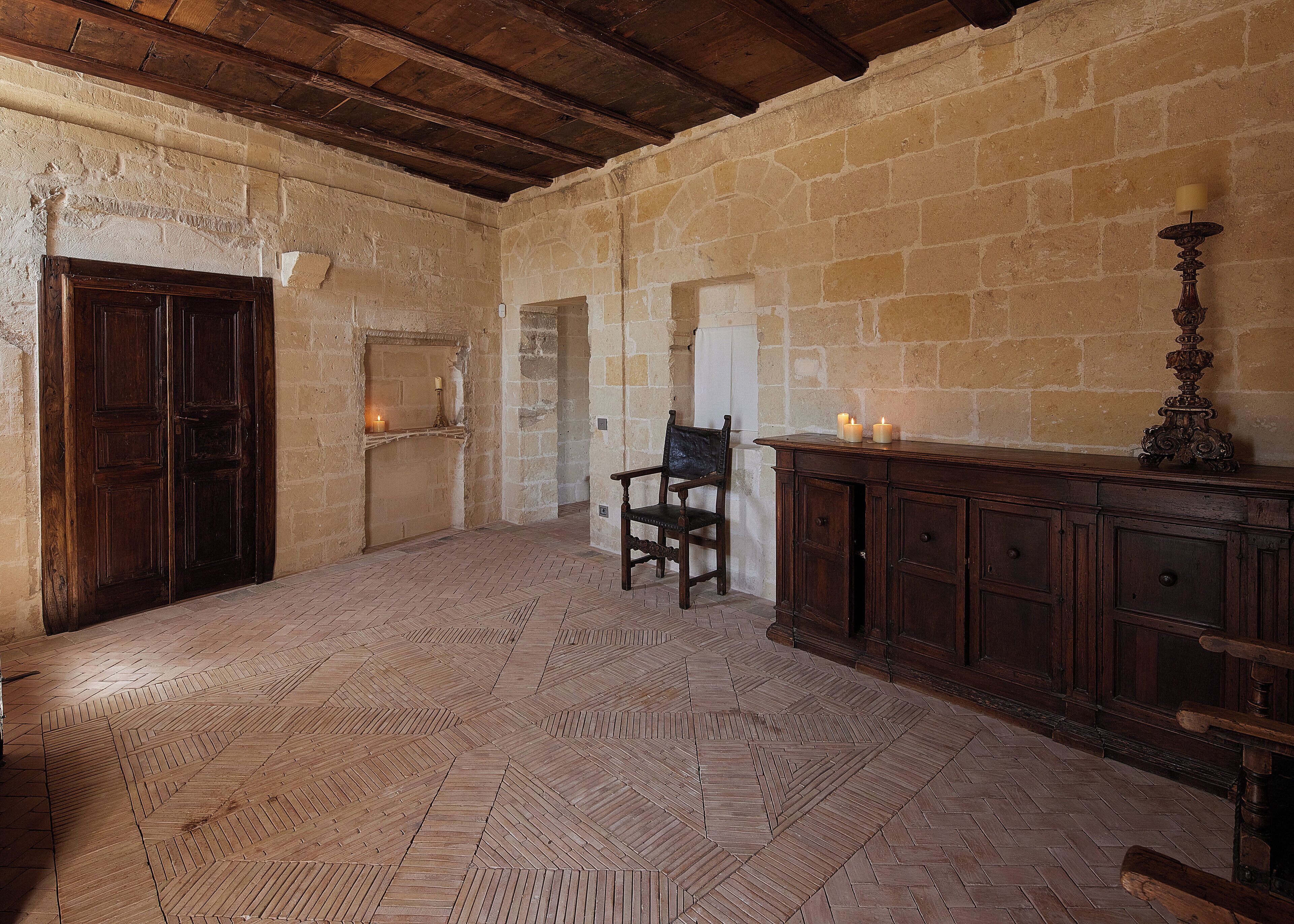 A room with a wooden door, a chair, a cabinet, and a tiled floor.