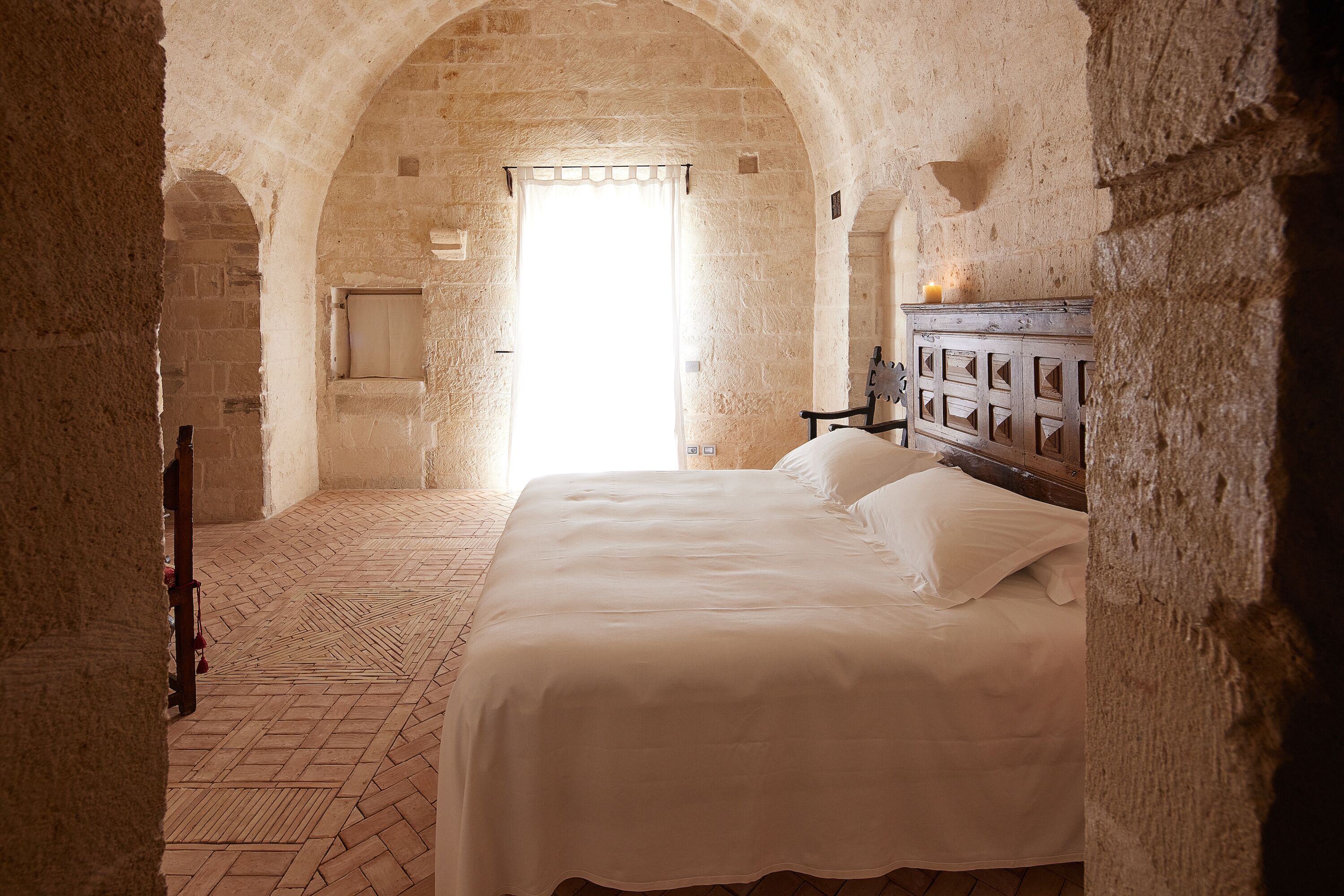 Una habitación con una cama, un armario de madera y un arco de entrada.