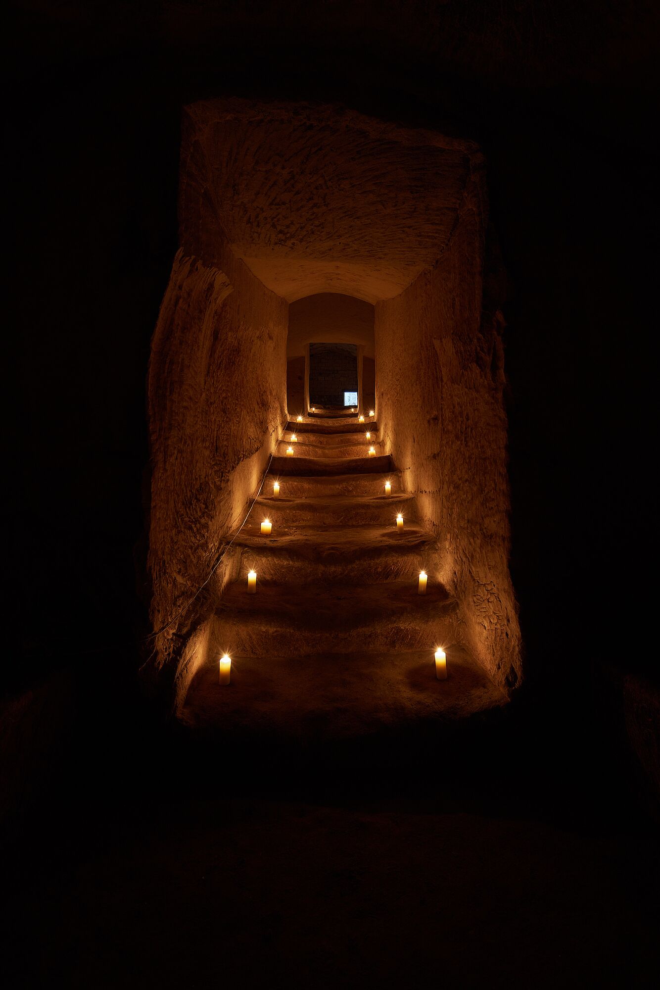 A dimly lit stone staircase leading to a small window at the top.