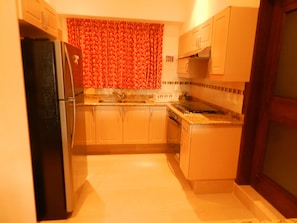 Una cocina compacta con refrigerador, estufa, pileta y alacenas.