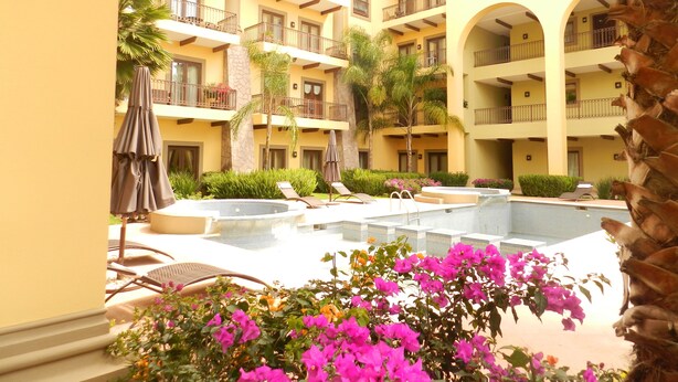 Un hotel de varios pisos con balcones, piscina y zonas de estar al aire libre.