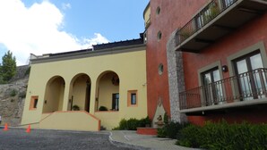 Un edificio con fachada amarilla, varios arcos y una sección roja con un balcón.