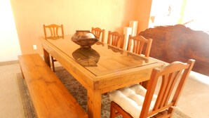 Una mesa de madera para comer con sillas y un banco, rodeada por un tapete estampado.
