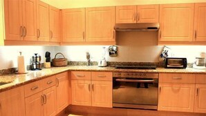Una cocina con armarios de madera, horno de acero inoxidable y encimera de granito.
