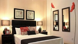 Una habitación de hotel con una cama grande, dos mesitas de noche y dos espejos en la pared.