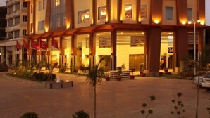 Et hotel med flere etager, altaner, store vinduer og et godt oplyst indgangsparti.