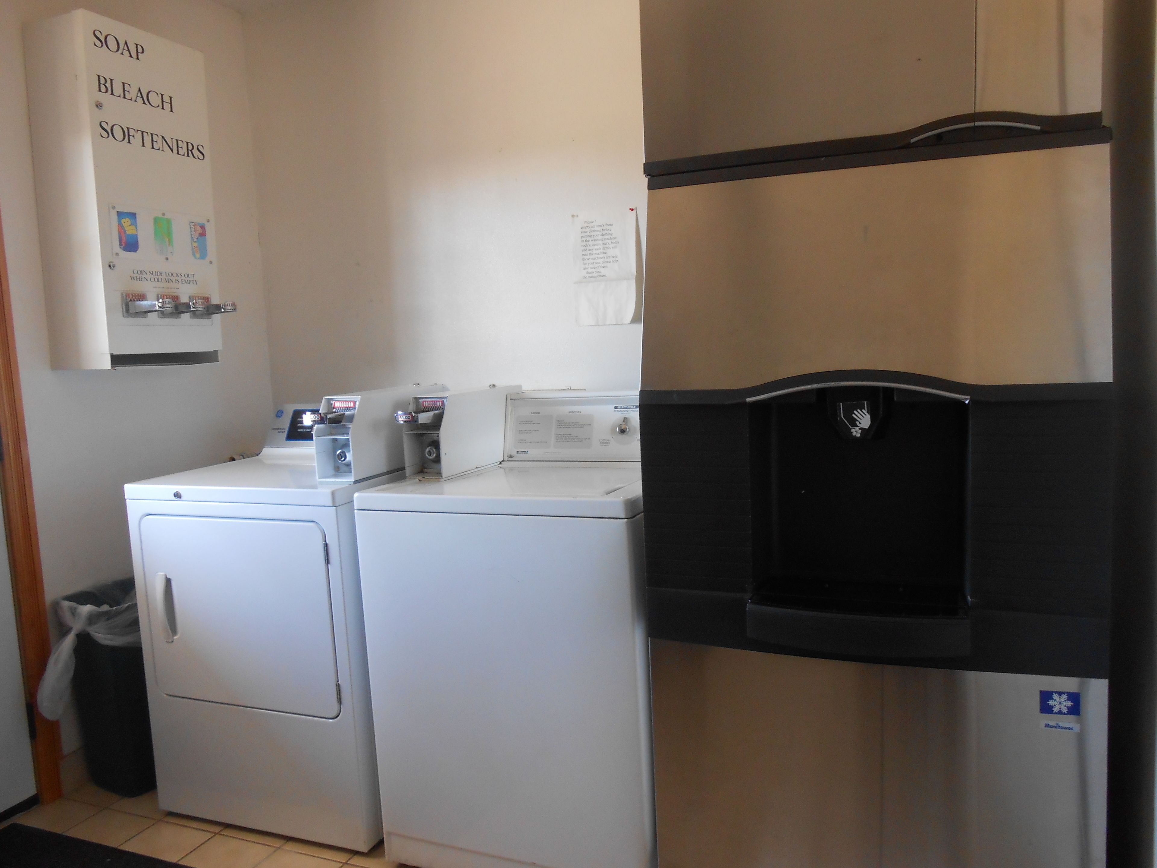 A laundry area with two front-loading washers and a black refrigerator.
