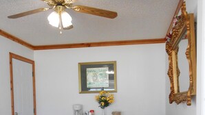 A living room with a ceiling fan, a coffee maker, a framed picture, and a patterned sofa. - Budget Inn Siloam Springs (Siloam Springs)