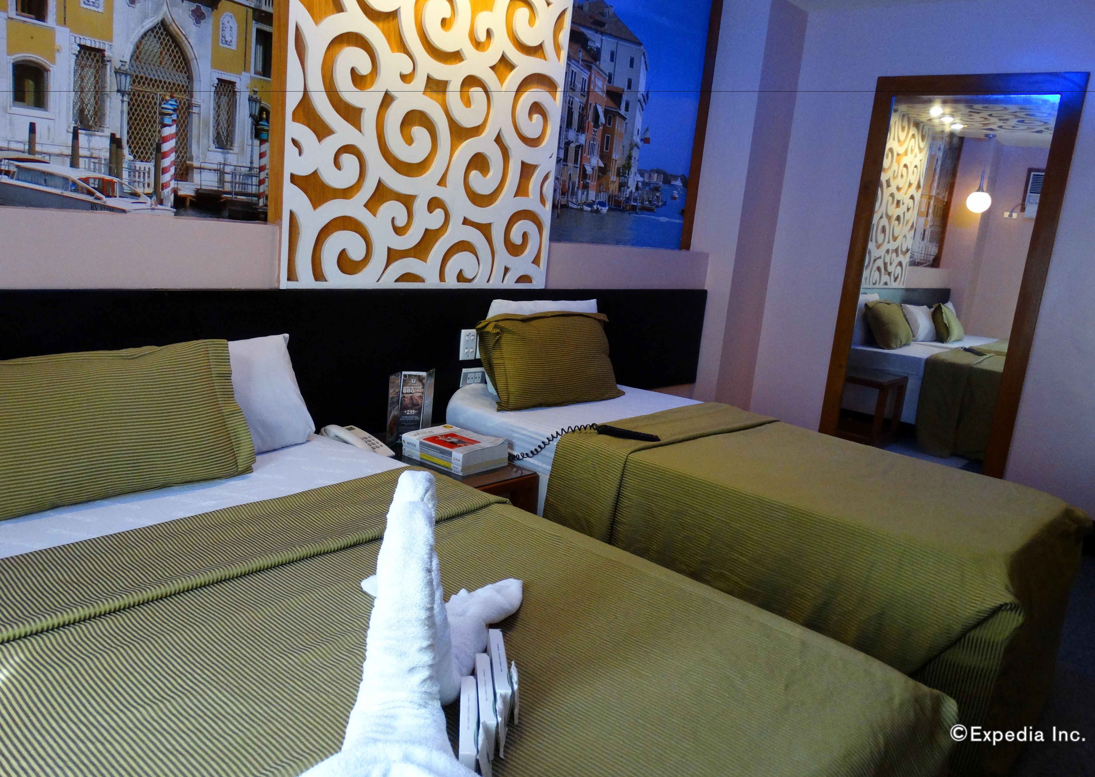 Ein Hotelzimmer mit zwei Betten, einem Nachttisch, einem Spiegel und einer dekorativen Wandverkleidung.