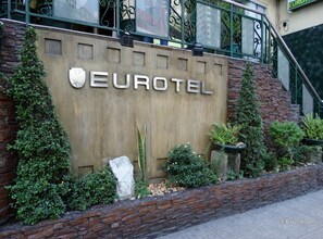 Eurotel-hotellin ulkoasu: kiviverhous, metallinen kyltti ja ympäröivä viheralue.