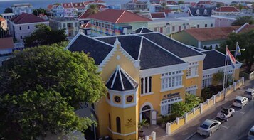 A yellow building with a tower, a sign reading "Kloster", and a street with parked cars.
