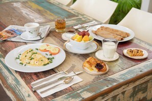 Una mesa con alimentos para el desayuno, como huevos, tostadas, fruta y un vaso de leche.