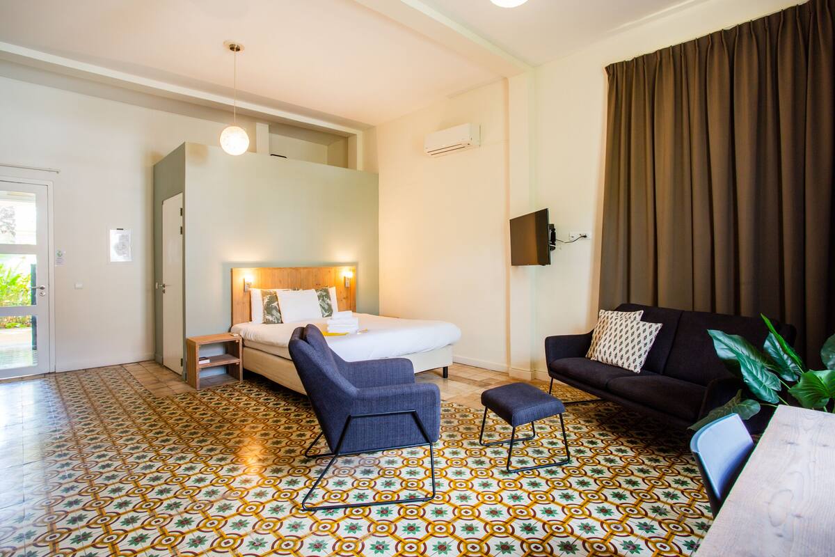 A hotel room with a bed, a sofa, a small table, and a TV.