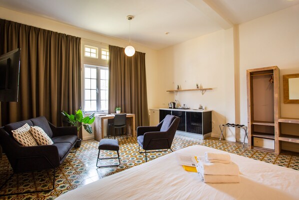 A hotel room with a bed, a sofa, a desk, a chair, a television, and a wardrobe. - Boutique Hotel t Klooster (Willemstad)