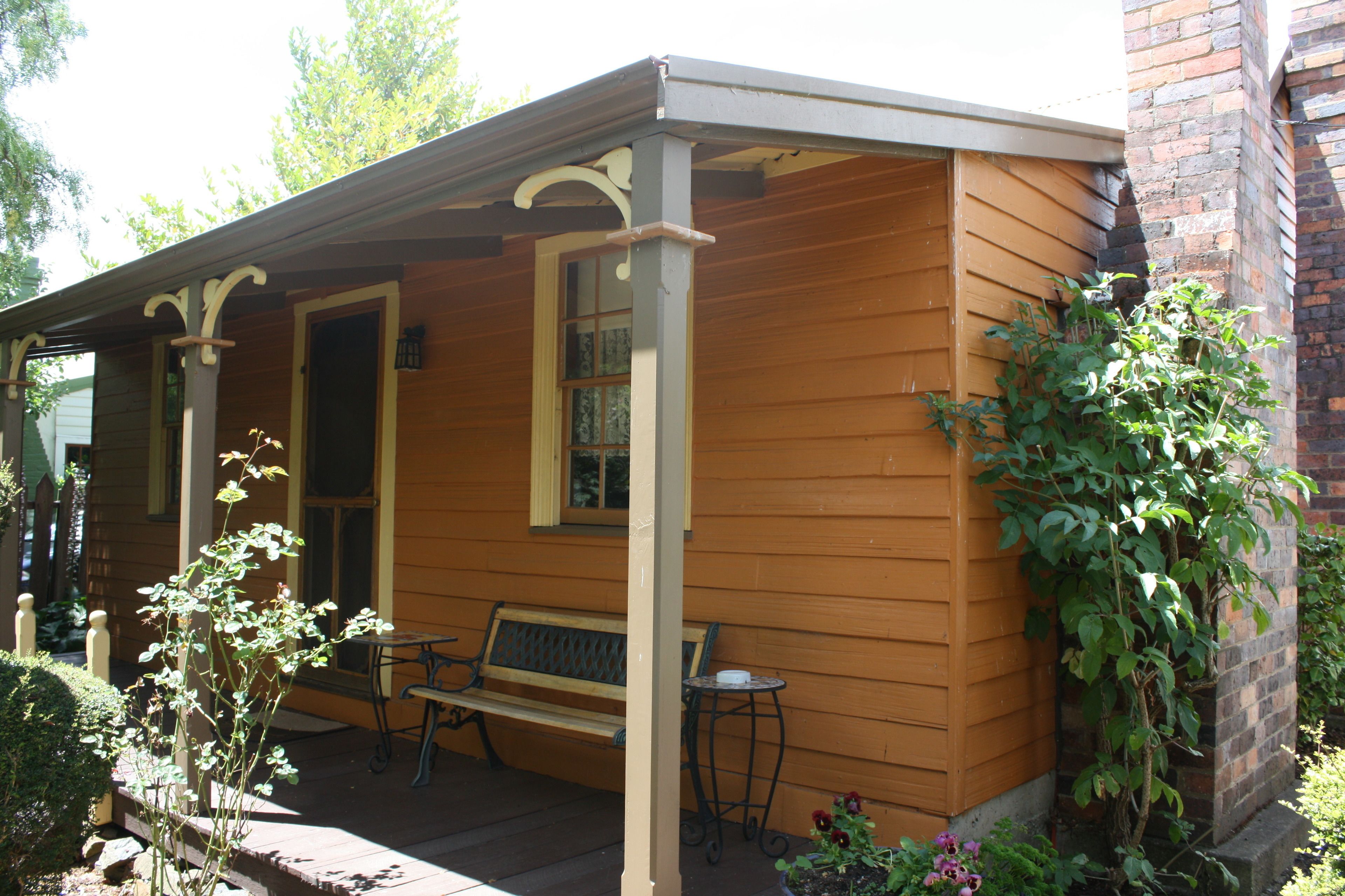 A wooden house with a porch, a bench, and a table.