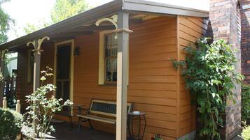 A wooden house with a porch, a bench, and a table.