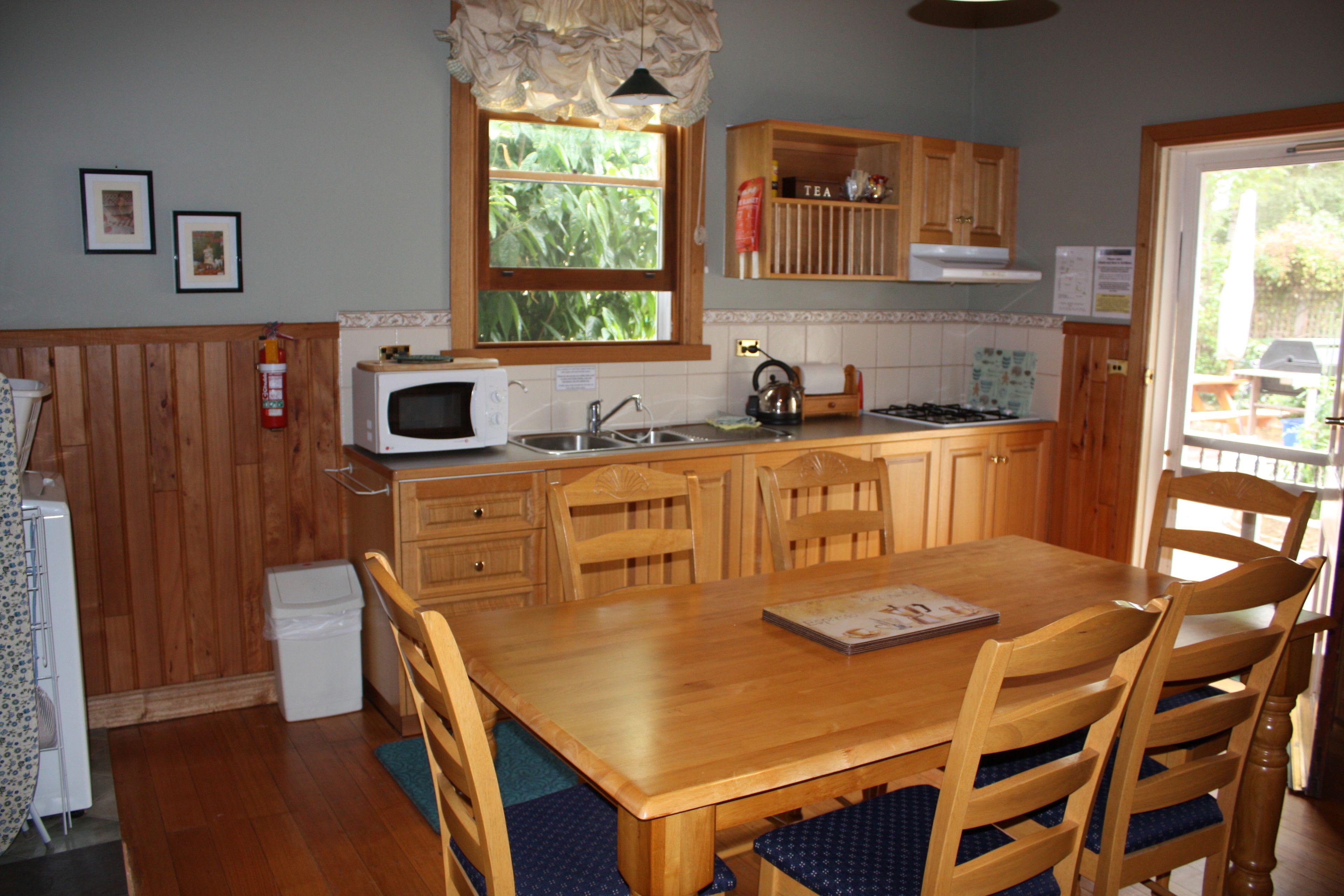 A kitchen with wooden cabinets, a microwave, a gas stove, and a dining table with chairs.