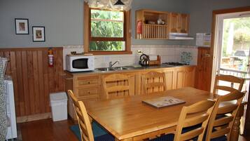 A kitchen with wooden cabinets, a microwave, a gas stove, and a dining table with chairs.